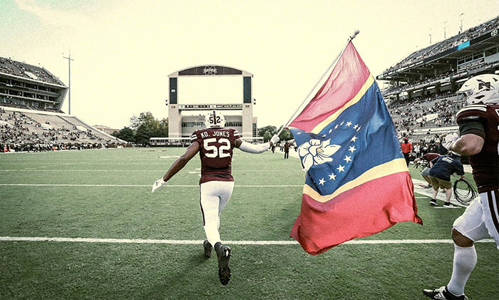 Mississippi State University football player Kobe Jones running on the field with the new state flag